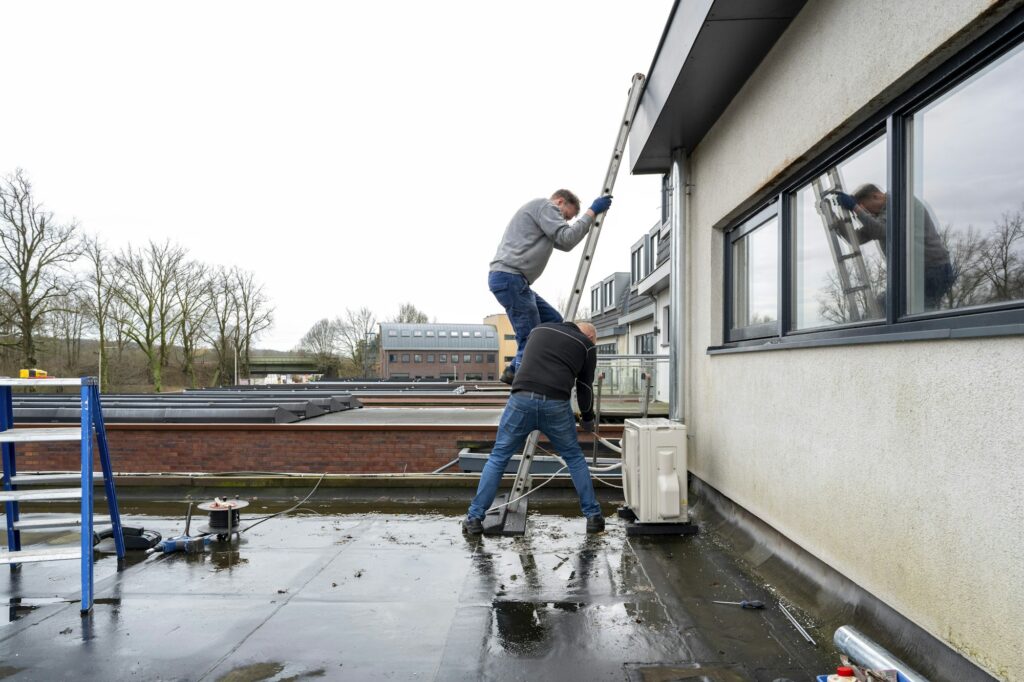 Two workers installing a window on an overcast day.